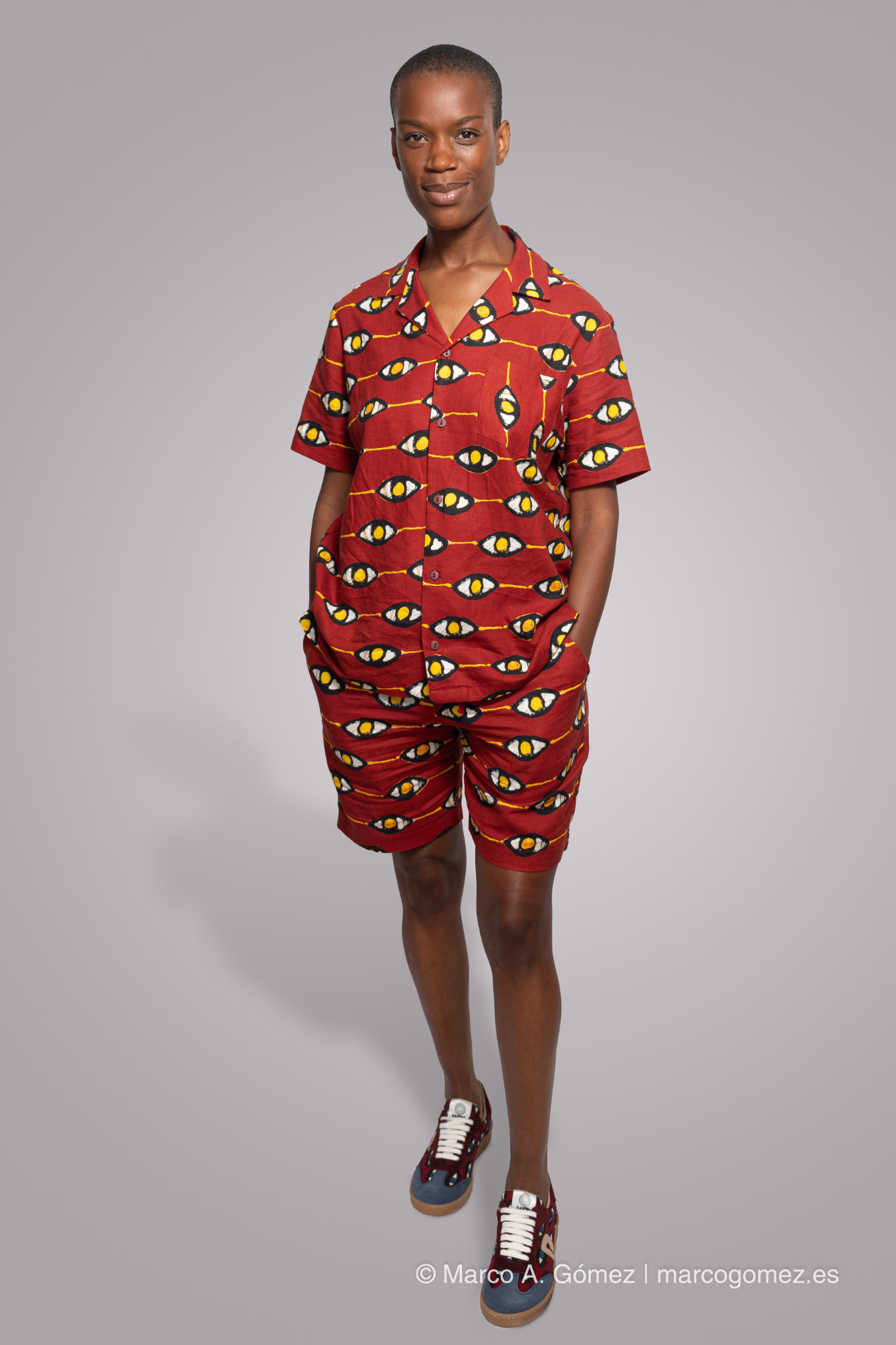 Proyecto integral Modelo luciendo conjunto de camisa y pantalón corto con patrón gráfico de ojos en estudio para el proyecto Dakart.
