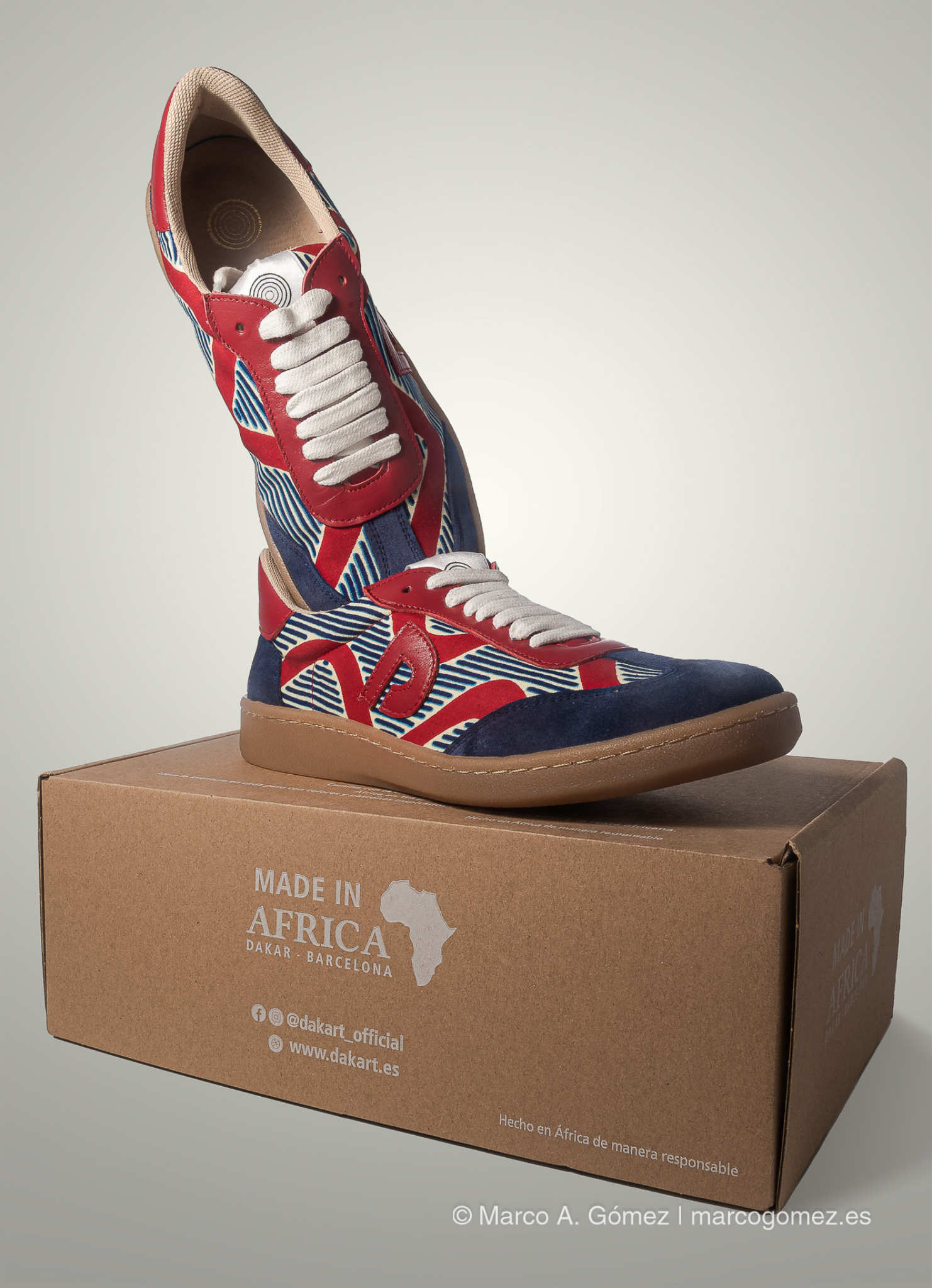 Proyecto integral Zapatilla de la colección Dakart posada sobre su caja de cartón oficial con el logotipo de la marca por Marco A. Gómez.