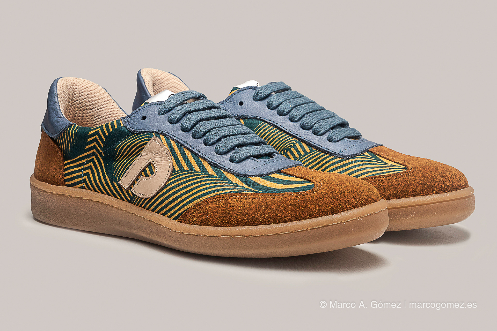 Proyecto integral Par de zapatillas de diseño artesanal en tonos azul, verde y ante marrón, con cordones celestes y el logotipo de la marca Dakart.
