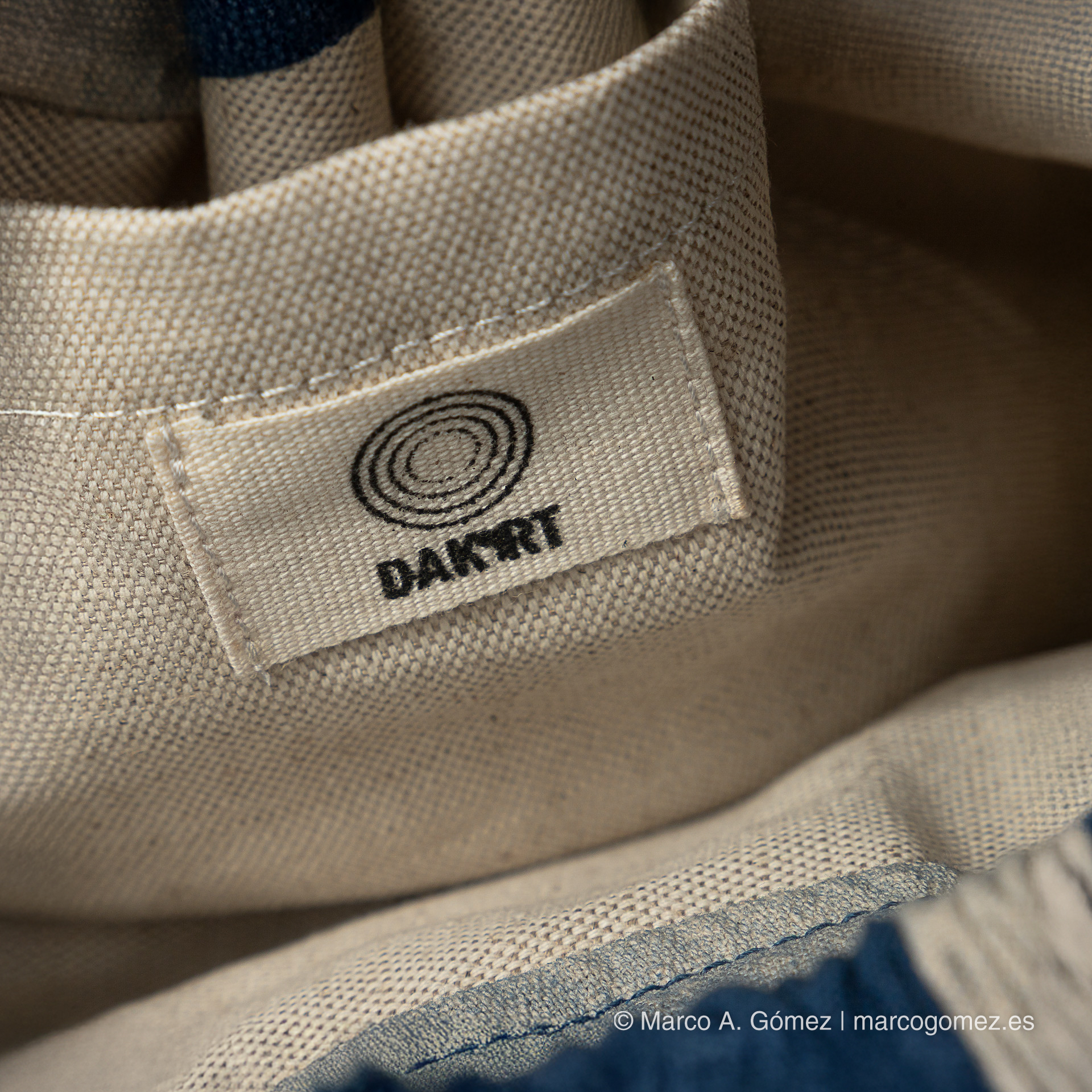 Proyecto integral Detalle de la etiqueta interior con el logotipo circular de la marca Dakart en un bolso artesanal.