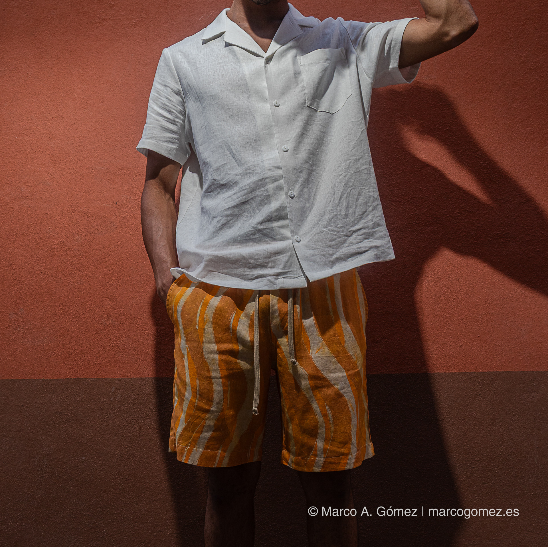 Proyecto integral Modelo con camisa blanca de lino y pantalones cortos estampados en la sesión exterior urbana de Dakart.