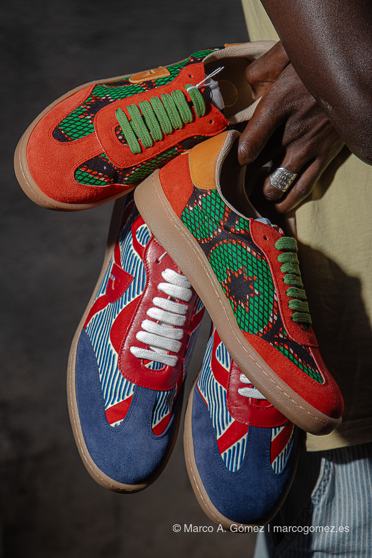 Proyecto integral Manos sosteniendo varios modelos de zapatillas coloridas de la colección de calzado del proyecto Dakart.